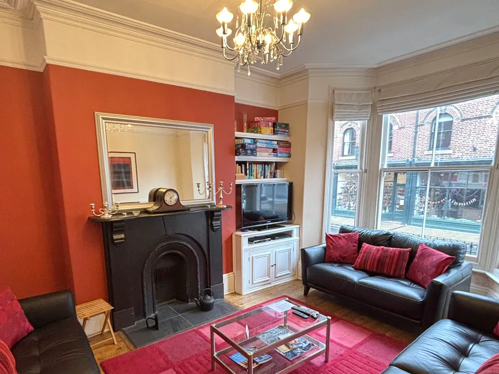 The living room at Minster Bells, with a black Victorian fireplace, chandelier and a bay window onto Gillygate