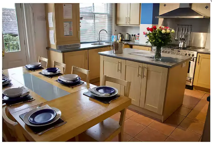The kitchen at Minster Bells, with a central island, range cooker and dining table laid for a meal