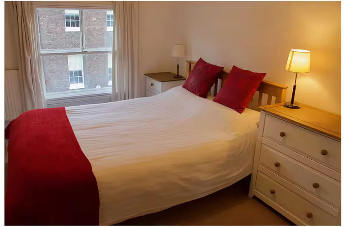 A cosy double bedroom with a sash window overlooking the street